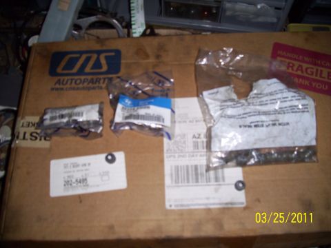 1995 Ford Probe - Several small automotive parts are laid out on a cardboard box, some in plastic packaging.