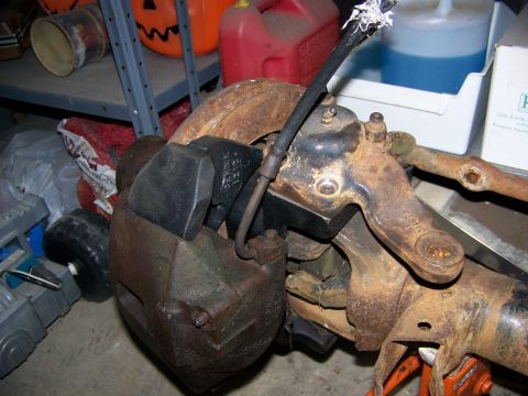 1992 Jeep YJ - Close-up of corroded vehicle brake and steering components stored indoors.