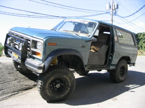 1986 Ford Bronco - This modified Ford Bronco sits on a gravel incline with its driver's door ajar.