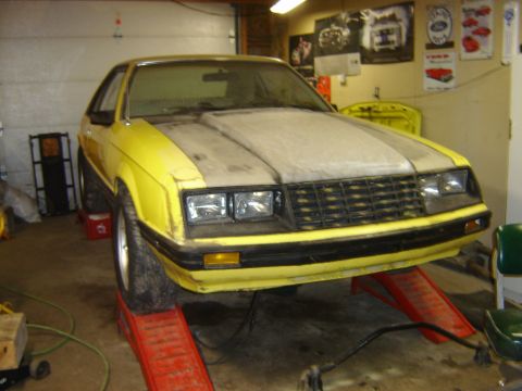 1979 Ford Mustang - Front view of a yellow 1979 Ford Mustang undergoing maintenance in a garage.