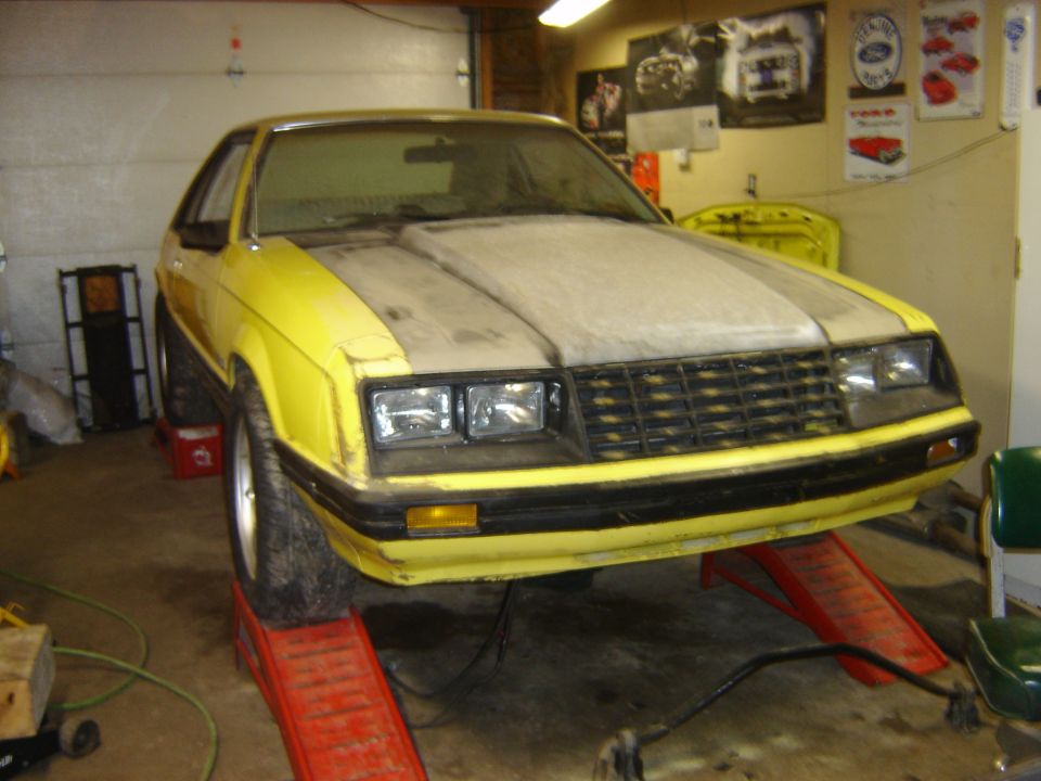 1979 Ford Mustang front end on red ramps in garage