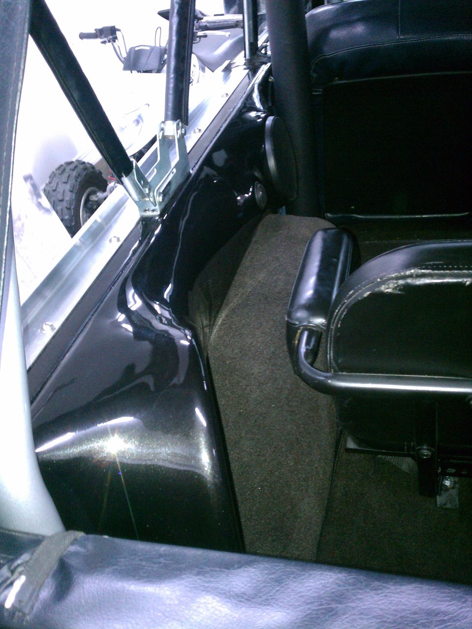 Bronco interior with black bucket seat, carpeted console, and roll bar mount