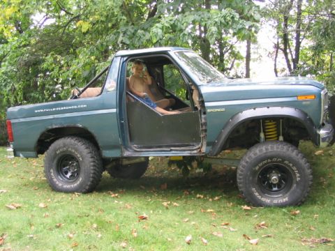 1986 Ford Bronco - This Ford Bronco has a roll cage and off-road tires, with the doors removed for an open-air feel.
