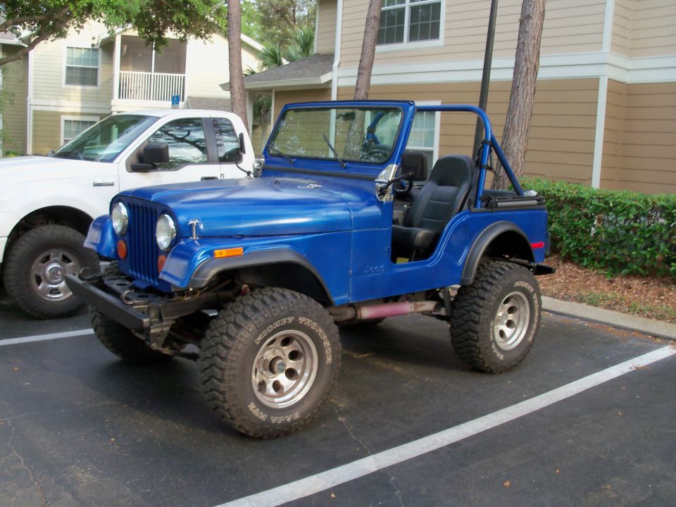 Blue Jeep CJ parked next to a white pickup truck
