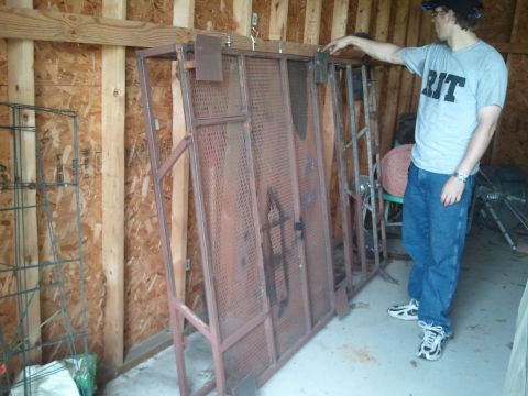 1995 Ford Bronco - A person stands beside a large, rusty metal rack that is leaning against a wall in a garage.