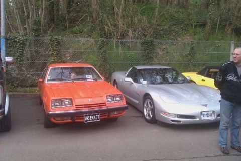 1991 Ford LTD Crown Victoria - Two cars, an orange coupe and a silver sports car, are parked next to each other at an outdoor event.