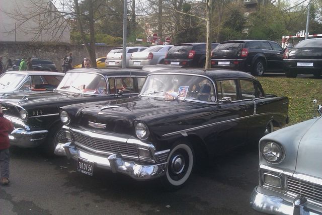 Black 1956 Chevrolet sedan parked next to other cars