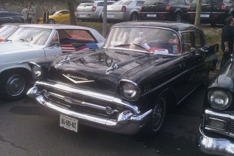 1991 Ford LTD Crown Victoria - A black 1957 Chevrolet Bel Air four-door sedan seen from the front three-quarter at an outdoor car meet, showing the chrome grille, bullet…