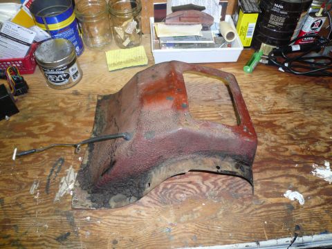 1975 Ford Ranchero - A heavily rusted car part, possibly from the undercarriage, rests on a cluttered workbench.