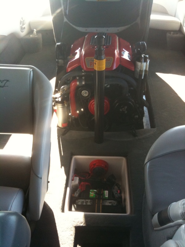 Open engine hatch on a ski boat showing red inboard engine and battery locker
