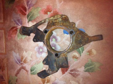 1972 Ford Ranchero - A heavily rusted steering knuckle is shown against a floral patterned fabric. The part appears to be from an older vehicle.