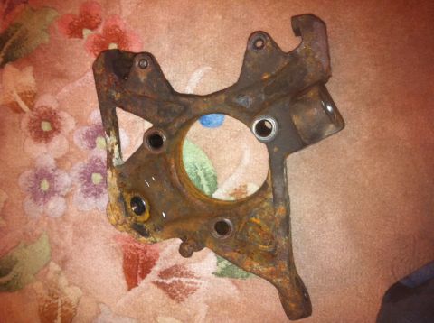 1972 Ford Ranchero - A heavily rusted metal part, likely a steering knuckle, lies on a floral patterned fabric.