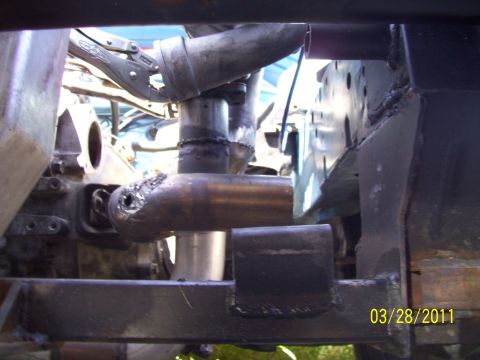 1995 Ford Probe - Welding is being performed on the vehicle's frame, attaching a pipe fitting.