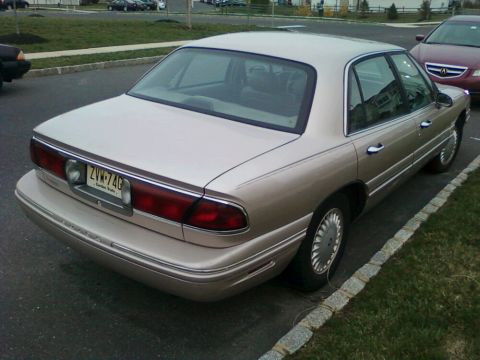 2004 Acura TL - A tan sedan is parked on the side of the road, with another car visible in the background.