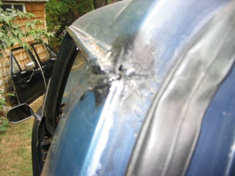 1986 Ford Bronco - A close-up of a damaged blue vehicle roof shows significant creasing and rust damage.