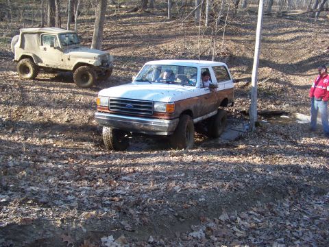 1989 Ford Bronco - This 1989 Ford Bronco is navigating a muddy trail with another off-road vehicle in the background.
