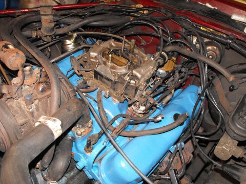 1982 Chrysler New Yorker - Engine bay detail showing a carburetor and associated plumbing, likely during a reassembly process.