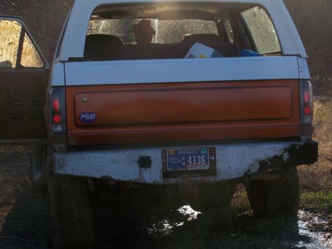 1989 Ford Bronco - The rear of a Ford Bronco shows an Indiana license plate and an orange tailgate panel.