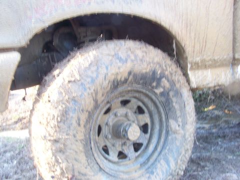1989 Ford Bronco - This close-up shows a heavily mud-caked tire and wheel well, suggesting off-road use.