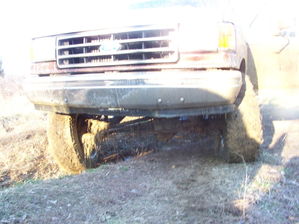 1989 Ford Bronco front grille and bumper covered in mud, front wheel visible