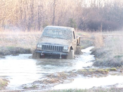 1989 Ford Bronco - This Jeep Cherokee is deep in mud and water, struggling to get through the terrain.