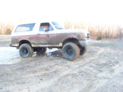 1989 Ford Bronco - This 1989 Ford Bronco navigates a muddy terrain, showing its off-road capabilities.
