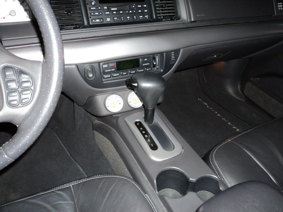 Car interior with automatic shifter, aftermarket gauges, and steering wheel controls
