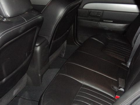 2004 Mercury Grand Marquis - The rear interior of a car shows black leather seats with white stitching and a dark door panel.