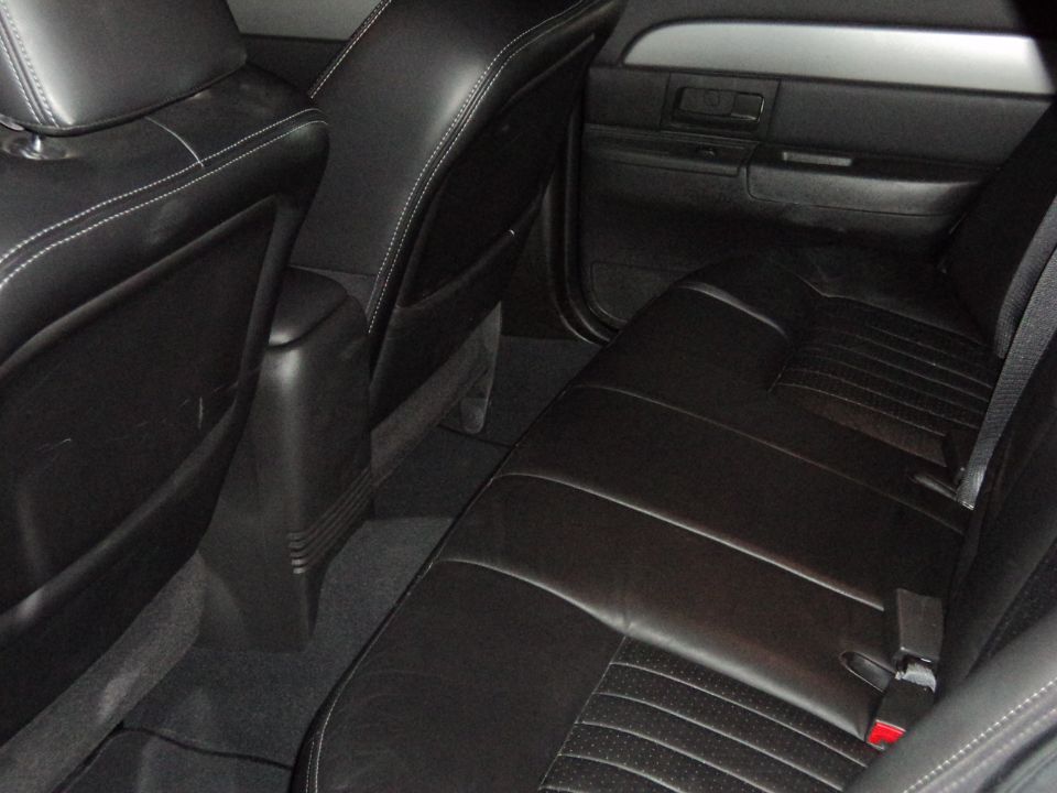 Black leather rear bench seat with white contrast stitching in a full-size sedan