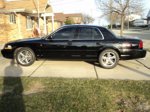 2004 Mercury Grand Marquis - Side profile of a black 2004 Mercury Grand Marquis sedan with custom chrome wheels.