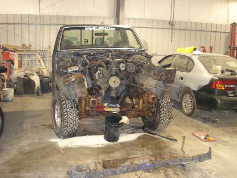 1993 Ford F-150 - A disassembled truck sits in a garage next to another car, awaiting repairs.
