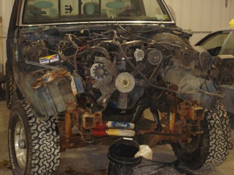 1993 Ford F-150 - Front view of a 1993 Ford F-150, disassembled to reveal the engine bay and heavily rusted chassis components.