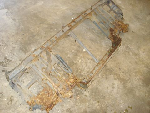 1993 Ford F-150 - A heavily rusted metal frame, likely a vehicle part, rests on a concrete surface.