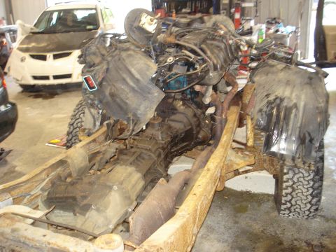 1993 Ford F-150 - Engine and transmission assembly on a rusty frame. Another vehicle is visible in the background.