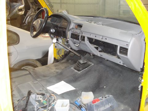 1993 Ford F-150 - The interior of a yellow 1993 Ford F-150 shows a dashboard in the process of restoration, with exposed wiring and components.