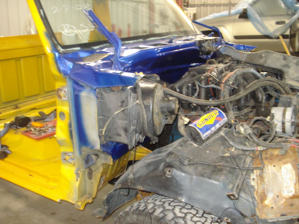 Truck engine bay with blue and yellow paint, "2-7-08" written on windshield