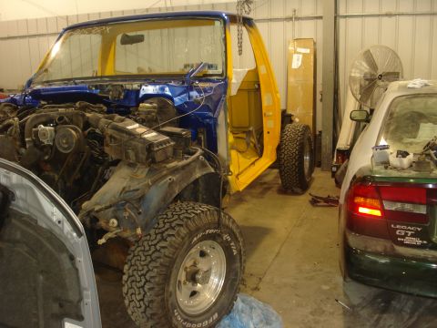 1993 Ford F-150 - A partially disassembled Ford F-150 truck is in a workshop, with another vehicle visible in the background.