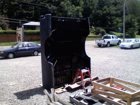1993 Ford F-150 - A black hood is open and resting on pallets, with a ladder nearby. Two other vehicles are visible in the background.
