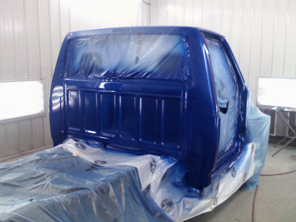 1993 Ford F-150 cab in a paint booth, covered in blue paint and plastic sheeting