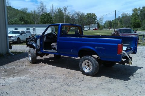 1993 Ford F-150 - A blue 1993 Ford F-150 pickup truck is shown from the front-three-quarter view, with its front end disassembled.
