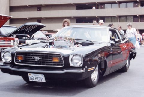1981 Ford Bronco - Modified 1975 Ford Mustang II with a prominent V8 engine on display at a car show.