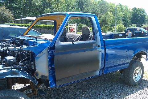 1993 Ford F-150 - A blue pickup truck is undergoing repairs with its front end disassembled and engine exposed.