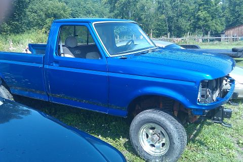 1993 Ford F-150 - This blue 1993 Ford F-150 pickup truck is seen from a 3/4 front angle, parked outdoors.