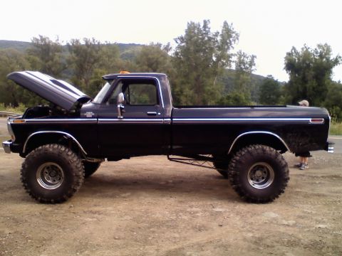 1993 Ford F-150 - Lifted black pickup truck with hood open, parked outdoors on a dirt surface.
