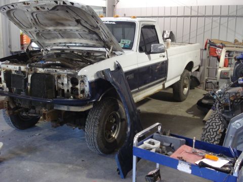 1993 Ford F-150 - This Ford F-250 is undergoing repairs in a garage, with its engine exposed and parts laid out.