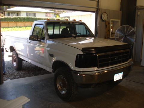1993 Ford F-150 - This white 1993 Ford F-150 pickup truck is parked inside a garage with the door partially open.
