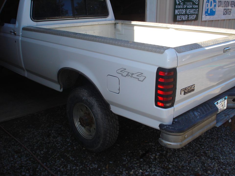 Rear quarter view of a white pickup truck with 4x4 badging and F250 emblem