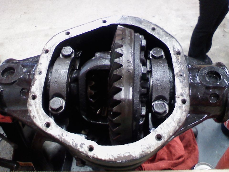 Differential housing with gears exposed, showing wear and grease. A red cloth is visible underneath