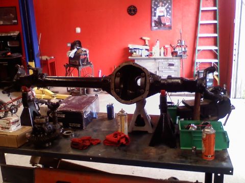 1993 Ford F-150 - A rear axle assembly is displayed on jack stands, surrounded by tools and parts in a garage setting.