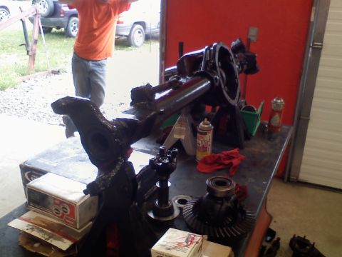 1993 Ford F-150 - Differential and axle components are laid out on a workbench, with a person and two SUVs in the background.